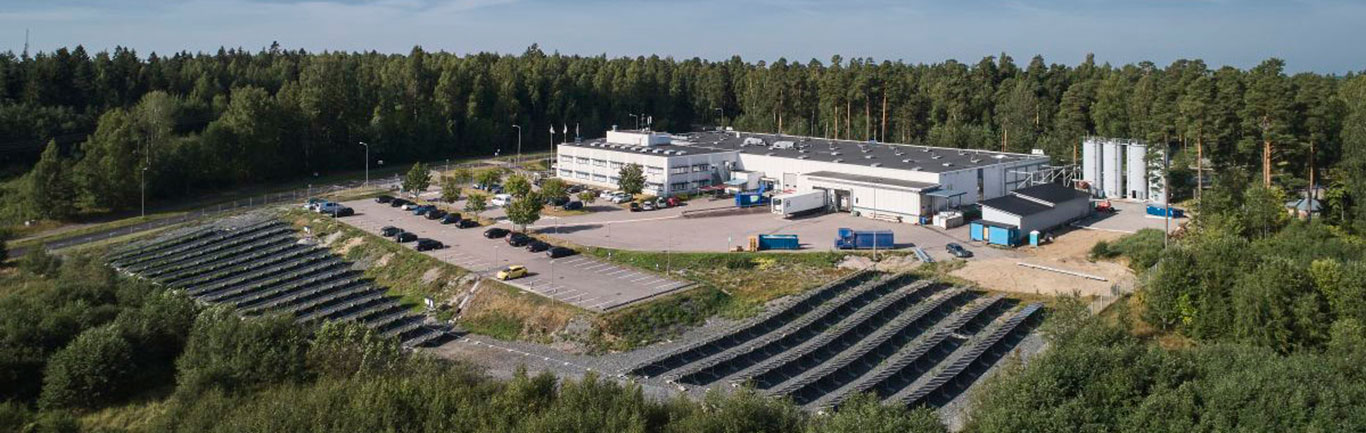 Ilmakuva ABB:n Porvoon tehtaasta, jota ympäröi metsä ja aurinkopaneelien rivistöt